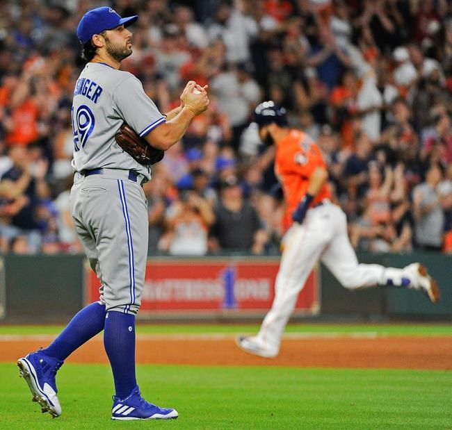 FILE - In this Aug. 4, 2017 file photo Toronto Blue Jays relief pitcher Mike Bolsinger, left, walks off the mound as Houston Astros' Marwin Gonzalez rounds the bases after hitting a three-run home run during the fourth inning of a baseball game in Houston. Bolsinger sued the Astros on Monday, Feb. 10, 2020 claiming their sign-stealing scheme contributed to a poor relief appearance August 2017 that essentially ended his big league career. (AP Photo/Eric Christian Smith, file)