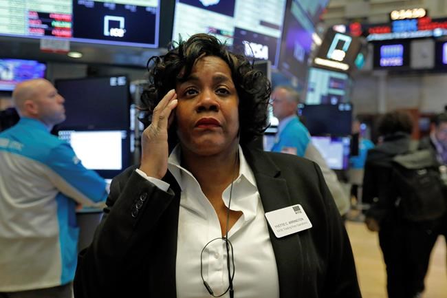 Yvette Arrington, with the New York Stock Exchange Trading Floor Operations, works on the floor of the NYSE, Monday, March 9, 2020. Stocks went into a steep slide Monday on Wall Street as coronavirus fears and a crash in oil prices spread alarm through the market, triggering the first automatic trading halt in over two decades. (AP Photo/Richard Drew)