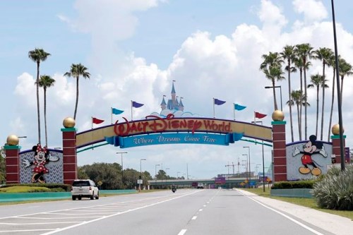 FILE - In this Thursday, July 2, 2020, file photo, cars drive under a sign greeting visitors near the entrance to Walt Disney World, in Lake Buena Vista, Fla. A new television show about the residents and caretakers at Walt Disney World's Animal Kingdom is being produced by National Geographic and will start streaming in the fall of 2020 on the Disney+. (AP Photo/John Raoux, File)