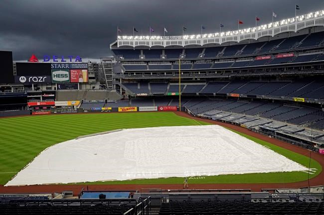 Storm clouds move over a tarp-covered field at Yankee Stadium where a baseball game between the New York Yankees and the Baltimore Orioles has been postponed due to inclement weather, Thursday, Sept. 10, 2020, in New York. The game was rescheduled for Friday afternoon as part of a doubleheader. (AP Photo/Kathy Willens)