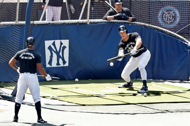New York Yankees Aaron Hicks, left, and Luke Voit, above right, watch as Aaron Judge begins his batting practice with a bunt at Yankees summer baseball training camp, Wednesday, July 15, 2020, at Yankee Stadium in New York. (AP Photo/Kathy Willens)