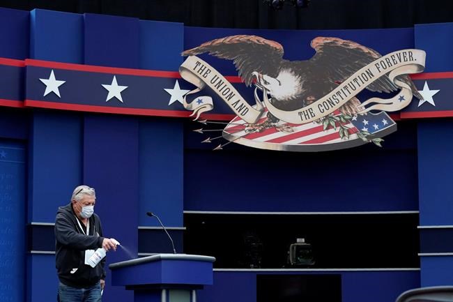 A worker sprays sanitizer on a lectern as preparations take place for the first Presidential debate in the Sheila and Eric Samson Pavilion, Monday, Sept. 28, 2020, in Cleveland. The first debate between President Donald Trump and Democratic presidential candidate, former Vice President Joe Biden is scheduled to take place Tuesday, Sept. 29. (AP Photo/Patrick Semansky)