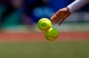 A Japanese softball player tosses the balls into a basket during a training session at the Fukushima Azuma Baseball Stadium ahead of the 2020 Summer Olympics, Tuesday, July 20, 2021, in Fukushima, Japan. (AP Photo/Jae C. Hong)