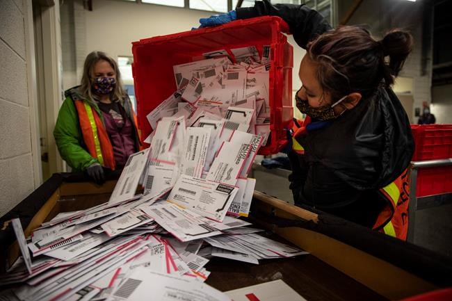 Election worker Kristen Mun from Portland empties ballots from a ballot box at the Multnomah County Elections Division, Tuesday, Nov. 3, 3030 in Portland, Ore. Oregon is the first state in the nation to institute voting by mail and automatic voter registration. (AP Photo/Paula Bronstein)