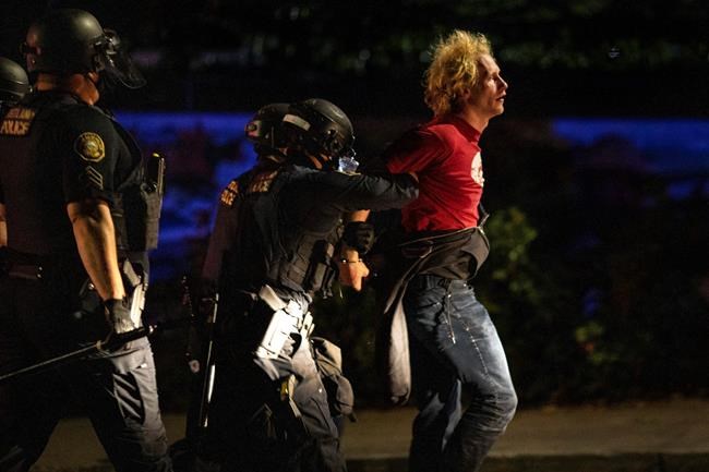 Portland police make arrests on the scene of the nightly protests at a Portland police precinct on Sunday, Aug. 30, 2020 in Portland, Ore. Oregon State Police will return to Portland to help local authorities after the fatal shooting of a man following clashes between President Donald Trump supporters and counter-protesters that led to an argument between the president and the city's mayor over who was to blame for the violence. (AP Photo/Paula Bronstein)