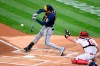 Milwaukee Brewers' Christian Yelich, left, hits a single during the first inning of a baseball game in front of Philadelphia Phillies' J.T. Realmuto (10), Monday, May 3, 2021, in Philadelphia. (AP Photo/Derik Hamilton)