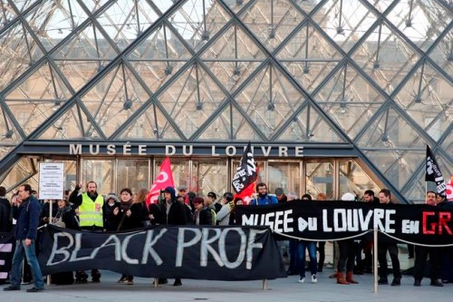 Striking employees hold banners outside the Louvre museum Friday, Jan. 17, 2020 in Paris. Paris' Louvre museum was closed Friday as dozens of protesters blocked the entrance to denounce the French government's plans to overhaul the pension system. (AP Photo/Francois Mori)