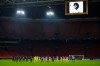 Ajax players, wearing black mourning arm bands, Midtjylland players and the referee and linesmen observe a minute of silence as they commemorate Argentinian soccer great Diego Maradona, picture seen above, prior to the group D Champions League soccer match between Ajax and Midtjylland at the Johan Cruyff ArenA in Amsterdam, Netherlands, Wednesday, Nov. 25, 2020. Maradona, who scored the 