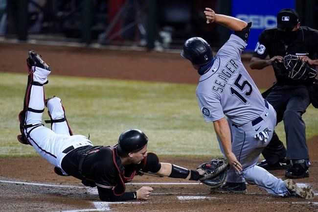 Seattle Mariners' Kyle Seager (15) scores as Arizona Diamondbacks catcher Carson Kelly, left, applies a late tag while umpire Nestor Ceja, right, watches during the first inning of a baseball game Saturday, Sept. 12, 2020, in Phoenix. (AP Photo/Ross D. Franklin)