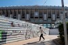 A woman wearing a protective mask walks past Real Madrid's Santiago Bernabeu stadium in Madrid, Spain, Friday, March 13, 2020. Real Madrid have said its players were being placed in isolation after one of the club's basketball players, who share facilities with Madrid's soccer players, tested positive for the COVID-19 coronavirus. That led to the instant decision by the Spanish league to bring matches to a halt for the next two rounds. For most people, the new coronavirus causes only mild or moderate symptoms. For some it can cause more severe illness, especially in older adults and people with existing health problems. (AP Photo/Paul White)