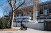 A man is pushed in the wheelchair while wearing protective masks near Real Madrid's Santiago Bernabeu stadium in Madrid, Spain, Friday, March 13, 2020. Real Madrid have said its players were being placed in isolation after one of the club's basketball players, who share facilities with Madrid's soccer players, tested positive for the COVID-19 coronavirus. That led to the instant decision by the Spanish league to bring matches to a halt for the next two rounds. For most people, the new coronavirus causes only mild or moderate symptoms. For some it can cause more severe illness, especially in older adults and people with existing health problems. (AP Photo/Paul White)