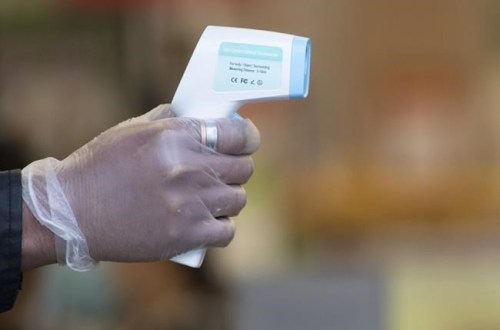 A grocery store security guard takes peoples temperatures prior to allowing them into the store in downtown Vancouver on Wednesday, April 29, 2020. THE CANADIAN PRESS/Jonathan Hayward
