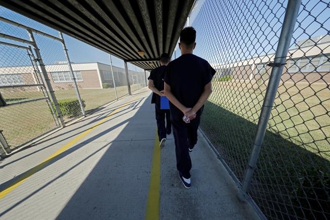 In a Thursday, Sept. 26, 2019 file photo, detainees walk with their hands clasped behind their backs along a line painted on a walkway inside the Winn Correctional Center in Winnfield, La. The Northwest Teritories says it has released a small number of prisoners over concerns about the possible spread of COVID-19 in territorial jails. THE CANADIAN PRESS/AP/Gerald Herbert, File