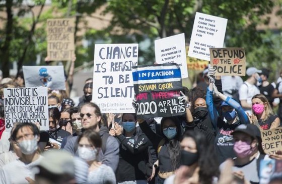 People hold up signs during a demonstration calling for justice for the death of George Floyd and victims of police brutality, in Montreal, Sunday, June 7, 2020. A new poll suggests more Canadians are questioning their trust in the police as protests against racism and police brutality sweep across much of North America. THE CANADIAN PRESS/Graham Hughes