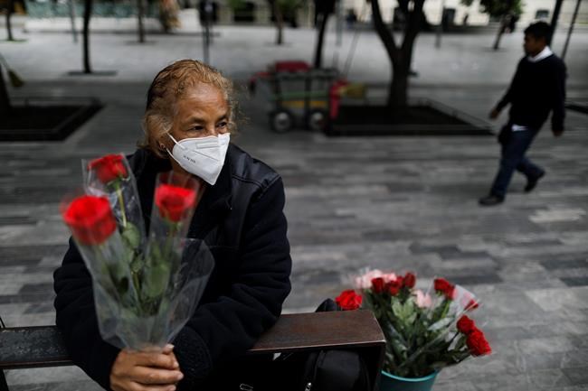 Wearing a mask to curb the spread of the new coronavirus, Martha Gonzalez Reyes, 76, sells roses outside Metro Hidalgo in central Mexico City, Monday, Aug. 10, 2020. After four months staying at home, Gonzalez returned to selling on August 1, but she says business hasn't fully rebounded.