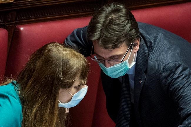 Lawmakers Matteo Dall'Osso, right, and Maria Teresa Baldini wear sanitary mask during a work session in the Italian lower chamber Tuesday, Feb. 25, 2020. Civil protection officials on Tuesday reported a large jump of cases in Italy, from 222 to 283. Seven people have died, all of them elderly people suffering other pathologies. (Roberto Monaldo/LaPresse via AP)
