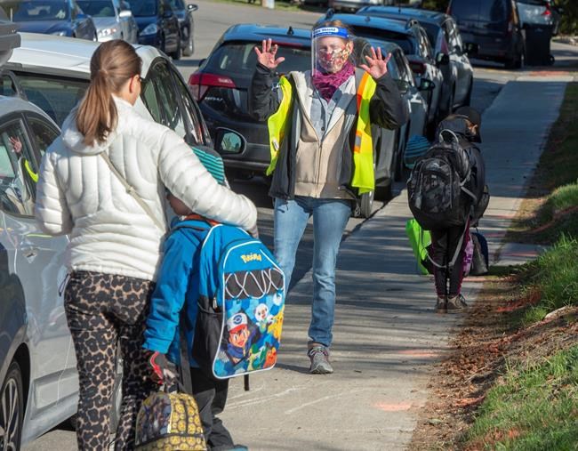 Teacher Janick Mille welcomes students at Ecole Marie Rose as elementary schools outside the greater Montreal area reopen Monday May 11, 2020 in Saint Sauveur, Que.. Schools and daycare centers have been closed due to the COVID-19 pandemic. THE CANADIAN PRESS/Ryan Remiorz