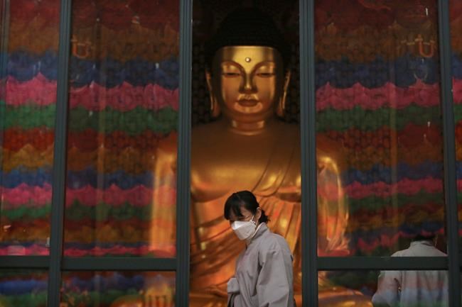 A Buddhist believer wearing a face mask leaves the Jogyesa Buddhist temple in Seoul, South Korea, Tuesday, Feb. 25, 2020. South Korea reported another large jump in new virus cases Monday a day after President Moon Jae-in called for