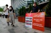 A protester stands to oppose South Korean President Moon Jae-in's possible visit to Japan in front of a building which houses Japanese embassy in Seoul, South Korea, Monday, July 19, 2021. Moon has decided not to visit Japan for the Tokyo Summer Olympics, citing a failure to set up a summit with Japan's prime minister that would produce meaningful results in improving relations. The signs on a banner at left read 