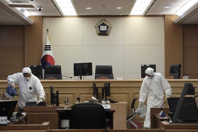 Workers wearing protective gears spray disinfectant as a precaution against the new coronavirus at Gwangju District Court in Gwangju, South Korea, Tuesday, Feb. 25, 2020. China and South Korea on Tuesday reported more cases of a new viral illness that has been concentrated in North Asia but is causing global worry as clusters grow in the Middle East and Europe. (Park Chul-hong/Yonhap via AP)