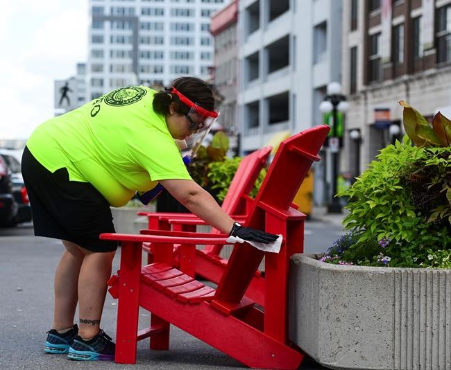 An employee disinfects a public chair in the Byward Market in downtown Ottawa on Monday, Aug. 17, 2020. THE CANADIAN PRESS/Sean Kilpatrick