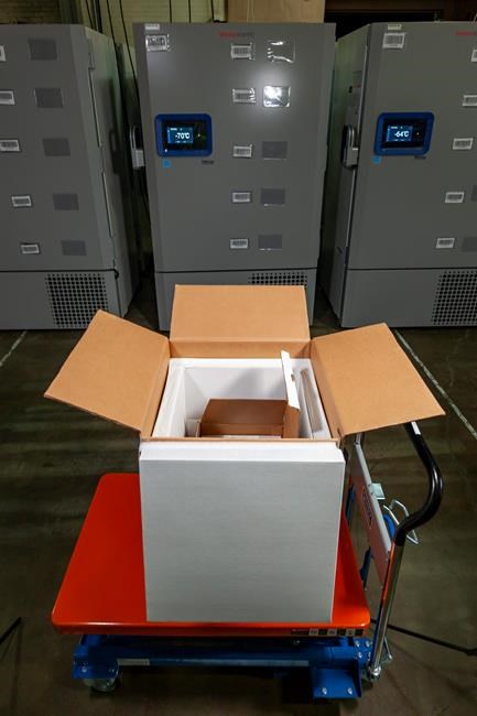 In this undated photo released by Pfizer on Tuesday, Dec. 1, 2020, a thermal shipping box for a COVID-19 candidate vaccine developed by BioNTech and Pfizer is shown in front of a freezers at the company headquarters in Puurs, Belgium. Pfizer and BioNTech say they've won permission Wednesday, Dec. 2, 2020, for emergency use of their COVID-19 vaccine in Britain, the world’s first coronavirus shot that’s backed by rigorous science -- and a major step toward eventually ending the pandemic. (Pfizer via AP)