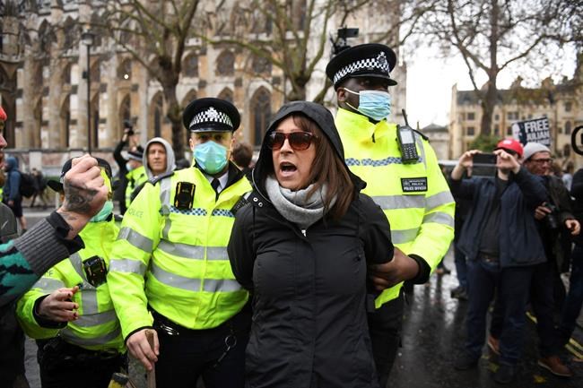 Police detain a woman taking part in an anti-vaccination and anti-lockdown protest in Parliament Square, London, Monday Dec. 14, 2020. (Stefan Rousseau/PA via AP)