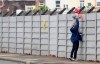 A man holds a child up over a fence to look into Liverpool's Melwood training ground after the English Premier League announced soccer players can return to training in small groups as the coronavirus lockdown was eased starting today Tuesday May 19, 2020. (Peter Byrne/PA via AP)