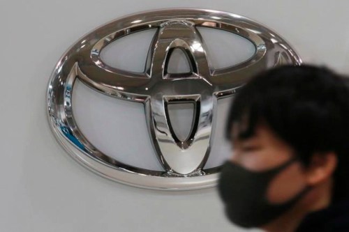 FILE - In this Nov. 2, 2020, file photo, visitor wearing a face mask to help curb the spread of the coronavirus walks by the logo of Toyota Motor Corp. at its showroom in Tokyo. Toyota won't be airing any Olympic-themed advertisements on Japanese TV during the Tokyo Games despite being one of the IOC's top corporate sponsors. The unusual decision by the country's top automaker underlines how polarizing the Games have become in Japan as COVID-19 infections rise ahead of the July 23, 2021, opening ceremony.(AP Photo/Koji Sasahara, File)