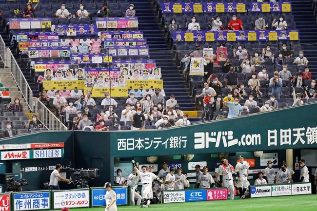 FILE - In this July 10, 2020, file photo, fans wearing face masks cheer as SoftBank Hawks' Nobuhiro Matsuda, center, celebrates after hitting a solo home run against Rakuten Golden Eagles in the second inning of a regular season baseball game in Fukuoka, southwestern Japan. Japan’s baseball and soccer leagues are ready to allow more fans into their games. The head of Japanese baseball and the soccer J-League on Tuesday, Sept. 8, 2020, said they are asking the government to allow a maximum of 20,000 fans, or up of 50% capacity — whichever number is smaller. (Kyodo News via AP, File)