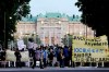 Protesters against the Tokyo Olympics gather outside Akasaka Palace, Japanese state guest house where the welcome party for IOC President Thomas Bach and its officials are held in Tokyo, Japan, Sunday, July 18, 2021. The banner, yellow, reads 