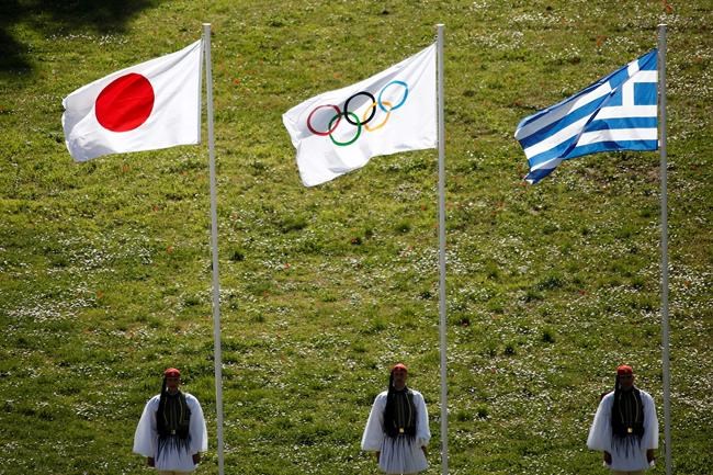 FILE - In this Thursday, March 12, 2020, file photo, Greek Evzones guards stand next to Japan, Olympic and Greece flags, from left, during the flame lighting ceremony at the closed Ancient Olympia site, birthplace of the ancient Olympics in southern Greece. U.S. President Donald Trump's suggestion to postpone the Tokyo Olympics for a year because of the spreading virus was immediately shot down by Japan's Olympic Minister Seiko Hashimoto. (AP Photo/Yorgos Karahalis, File)