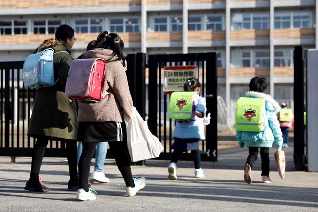 Students arrives at their elementary school in Sendai, northern Japan, Friday morning, Feb. 28, 2020, a day after Japanese Prime Minister Shinzo Abe's announcement. Abe asked all elementary, middle and high schools nationwide on Thursday to close until late March from March 2 to help control the spread of the new virus in the country. (Hironori Asakawa/Kyodo News via AP)