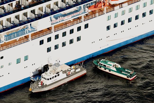 Japan Coast Guard's patrol boat, left, is brought alongside the cruise ship Diamond Princess to take passengers tested positive for coronavirus to hospitals off Yokohama, south of Tokyo, Wednesday, Feb. 5, 2020. Japan said Wednesday 10 people on the cruise ship have tested positive for the new virus and were being taken to hospitals. Health Minister Nobukatsu Kato said all the 3,700 people and passengers on the ship will be quarantined on board for up to 14 days under Japanese law. (Hiroko Harima/Kyodo News via AP)