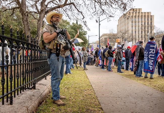 A supporters of President Donald Trump, who wished not to be identified, openly carries weapons while protesting the election, Wednesday, Jan. 6, 2021, at the Capitol in Austin, Texas. (Jay Janner/Austin American-Statesman via AP)
