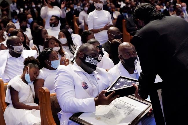 Houston Mayor Sylvester Turner hands a U.S. flag and a proclamation to Rodney Floyd, left, and Philonise Floyd during the funeral of their brother, George Floyd, at The Fountain of Praise church in Houston, Tuesday, June 9, 2020. (AP Photo/David J. Phillip, Pool)