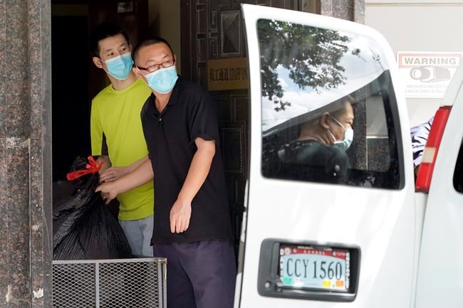 People remove bags from inside the Chinese Consulate to load into a van Thursday, July 23, 2020, in Houston. China says “malicious slander
