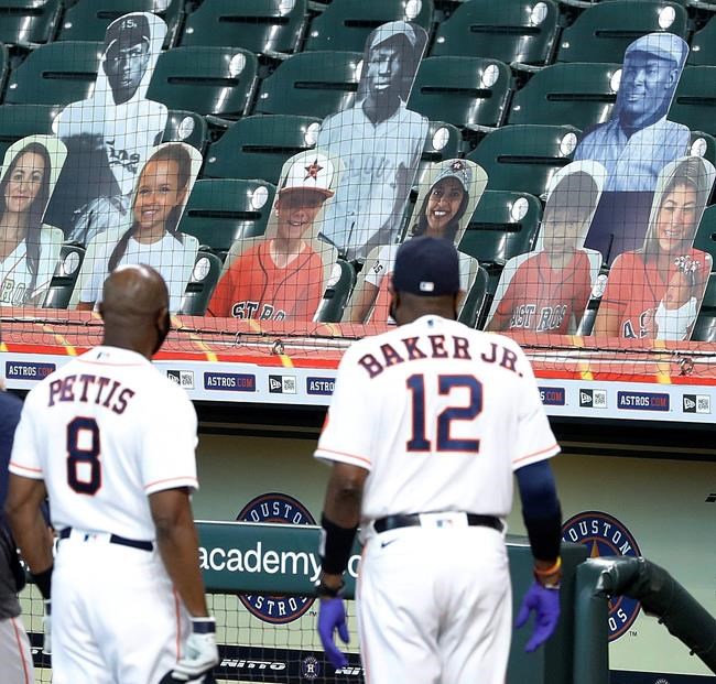 FILE - Houston Astros third base coach Gary Pettis and manager Dusty Baker Jr., look up into the stands at photo cutouts of former Negro League players during a celebration of the 100th Anniversary of the Negro Leagues before a game against the Seattle Mariners in Houston, in this Sunday, Aug. 16, 2020, file photo. Major League Baseball has reclassified the Negro Leagues as a major league and will count the statistics and records of its 3,400 players as part of its history. The league said it was “correcting a longtime oversight in the game’s history” by elevating the Negro Leagues on the centennial of its founding. (Kevin M. Cox/The Galveston County Daily News via AP, File)