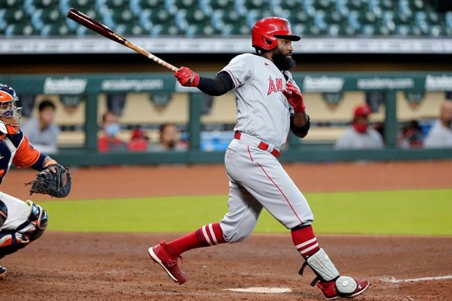 Los Angeles Angels right fielder Brian Goodwin, right, watches his one run double in front of Houston Astros catcher Martin Maldonado, left, during the inning of the first game of a doubleheader baseball game Tuesday, Aug. 25, 2020, in Houston. (AP Photo/Michael Wyke)