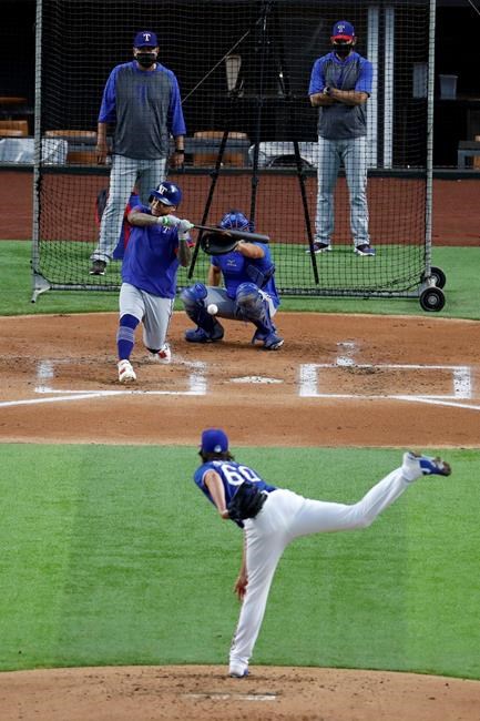 Texas Rangers' Luke Farrell throws to Willie Calhoun as catcher Jeff Mathis, pitching coach Julio Rangel, left rear and manager Chris Woodward, right rear, look on during a baseball practice at Globe Life Field in Arlington, Texas, Friday, July 3, 2020. (AP Photo/Tony Gutierrez)