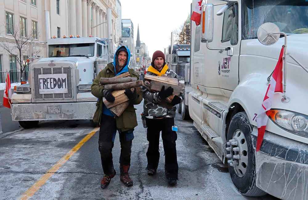 Truckers carry firewood for a stove they have in their trailer as a rally against COVID-19 restrictions, which began as a cross-country convoy protesting a federal vaccine mandate for truckers, continues in Ottawa, on Tuesday, February 1, 2022. THE CANADIAN PRESS/Patrick Doyle