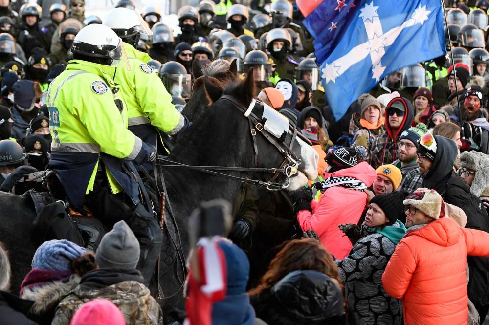 Protesters react as Toronto Police mounted unit charge to disperse as police take action to put an end to a protest, which started in opposition to mandatory COVID-19 vaccine mandates and grew into a broader anti-government demonstration and occupation, in Ottawa, Friday, Feb. 18, 2022. THE CANADIAN PRESS/Justin Tang