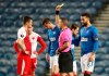 Slavia Prague's Ondrej Kudela, left, receives a yellow card during the UEFA Europa League Round of Sixteen soccer match at Ibrox Stadium, Glasgow, Thursday March 18, 2021. (Andrew Milligan/PA via AP)