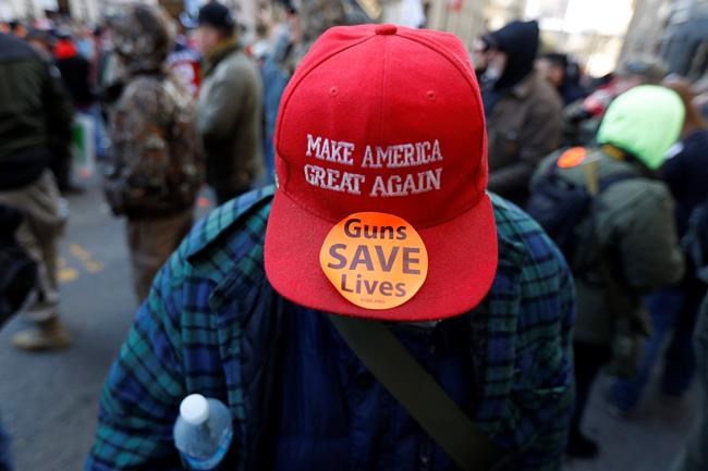 A man walks in the crowd during a pro-gun rally, Monday, Jan. 20, 2020, in Richmond, Va. Thousands of pro-gun supporters are expected at the rally to oppose gun control legislation like universal background checks that are being pushed by the newly elected Democratic legislature. (AP Photo/Julio Cortez)