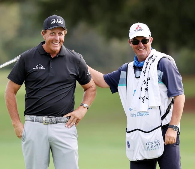 FILE - Winner Phil Mickelson gets a pat on the back from Jeff Johnson, the caddie for Retief Goosen, during final round play in the Dominion Energy Charity Classic at the Country Club of Virginia in Richmond, Virginia, in this Sunday, October 18, 2020, file photo. Lefty is back to the Champions Tour this weekend and has a chance to become the first player to win his first three career starts on a PGA-sanctioned tour. (Joe Mahoney/Richmond Times-Dispatch via AP, File)