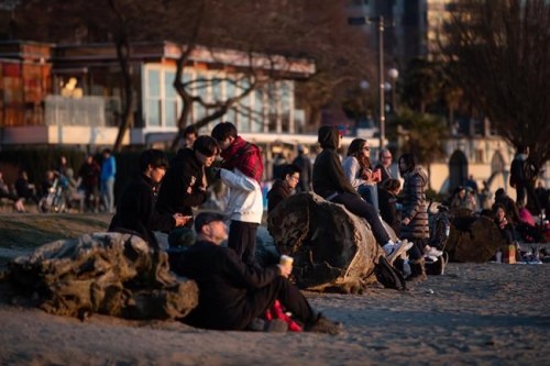 People take in the sunset at English Bay Beach, in Vancouver, on Saturday, March 21, 2020. The City of Vancouver asked those coming to the park and beach to maintain a distance of two metres between one another due to concerns about the spread of the coronavirus. THE CANADIAN PRESS/Darryl Dyck