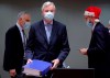 A collegue wears a Christmas hat as European Union chief negotiator Michel Barnier, center, carries a binder of the Brexit trade deal during a special meeting of Coreper, at the European Council building in Brussels, Friday, Dec. 25, 2020. European Union ambassadors convened on Christmas Day to start an assessment of the massive free-trade deal the EU struck with Britain. After the deal was announced on Thursday, EU nations already showed support for the outcome and it was expected that they would unanimously back the agreement, a prerequisite for its legal approval. (Olivier Hoslet, Pool via AP)