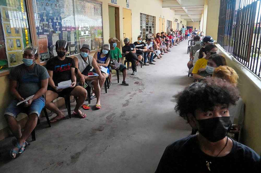 Residents wait to be inoculated with COVID-19 vaccines at a school during the first day of a nationwide three-day vaccination drive in Quezon city, Philippines on Monday, Nov. 29, 2021.  A strategy to protect Canadians would start by identifying the countries most in need of more vaccination and the people within those countries most susceptible to infection. (Aaron Favila / The Associated Press)