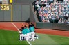 Seattle Mariners players kneel along the left field line with fists in the air as they watch a video tribute after the playing of the national anthem before the Mariners home opener baseball game against the Oakland Athletics Friday, July 31, 2020, in Seattle. (AP Photo/Elaine Thompson)
