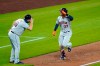 Houston Astros' Michael Brantley (23) shares a salute with third base coach Omar Lopez as Brantley heads toward home after hitting a solo home run against the Seattle Mariners during the sixth inning of a baseball game Tuesday, Sept. 22, 2020, in Seattle. (AP Photo/Elaine Thompson)